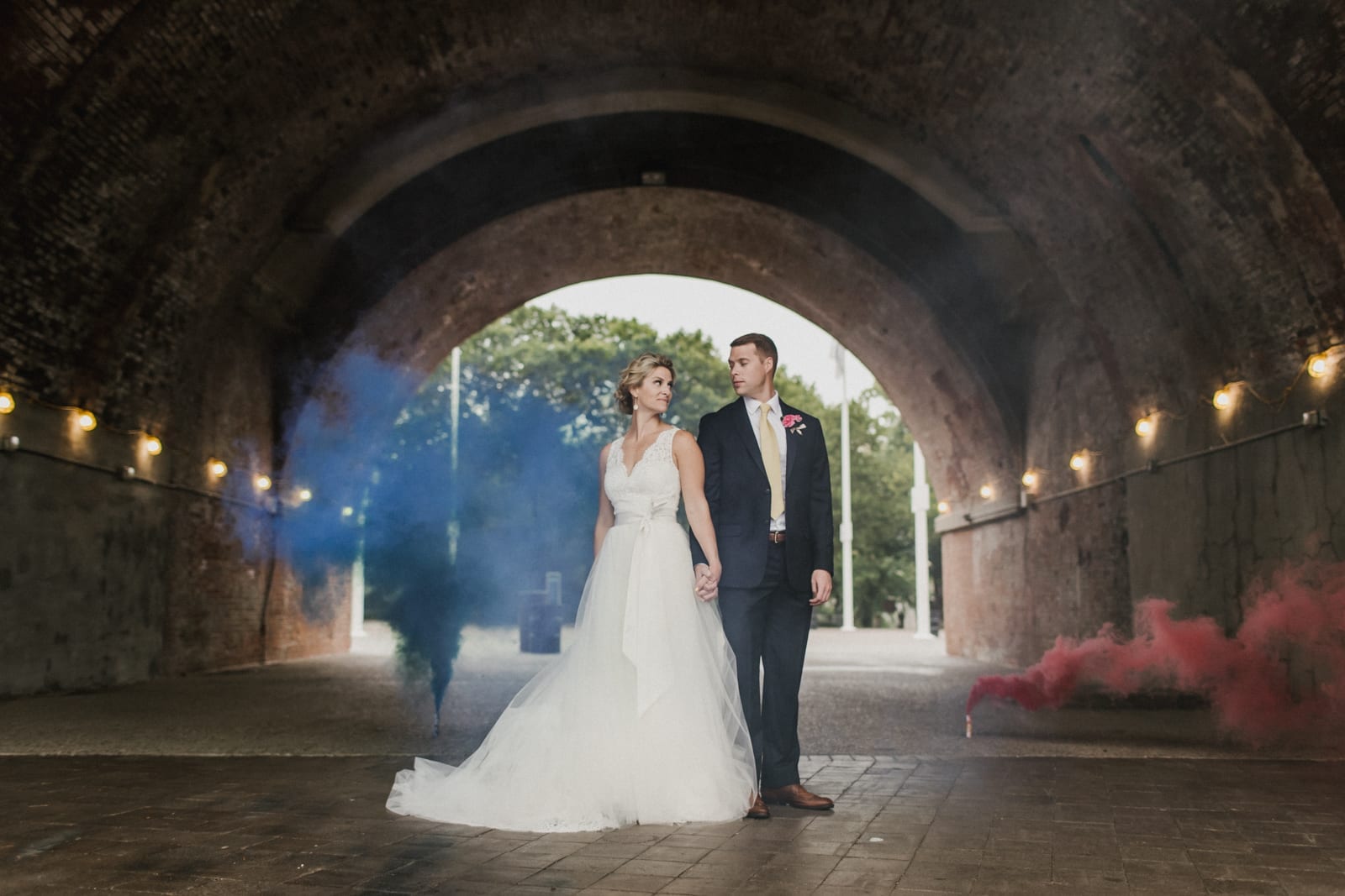 couple holding hands with smoke bombs in the background at The Monastery Wedding - Cincinnati Wedding Photographer
