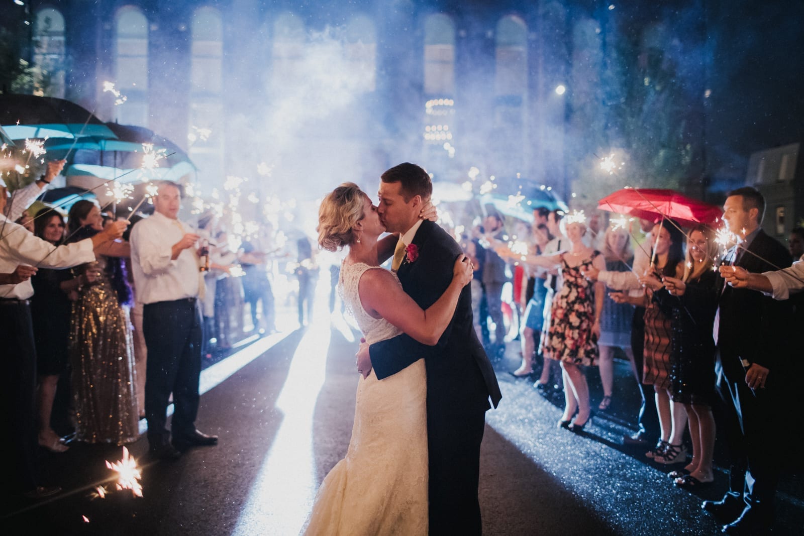 couple kisses while crowd holds sparklers at The Monastery Wedding - Cincinnati Wedding Photographer