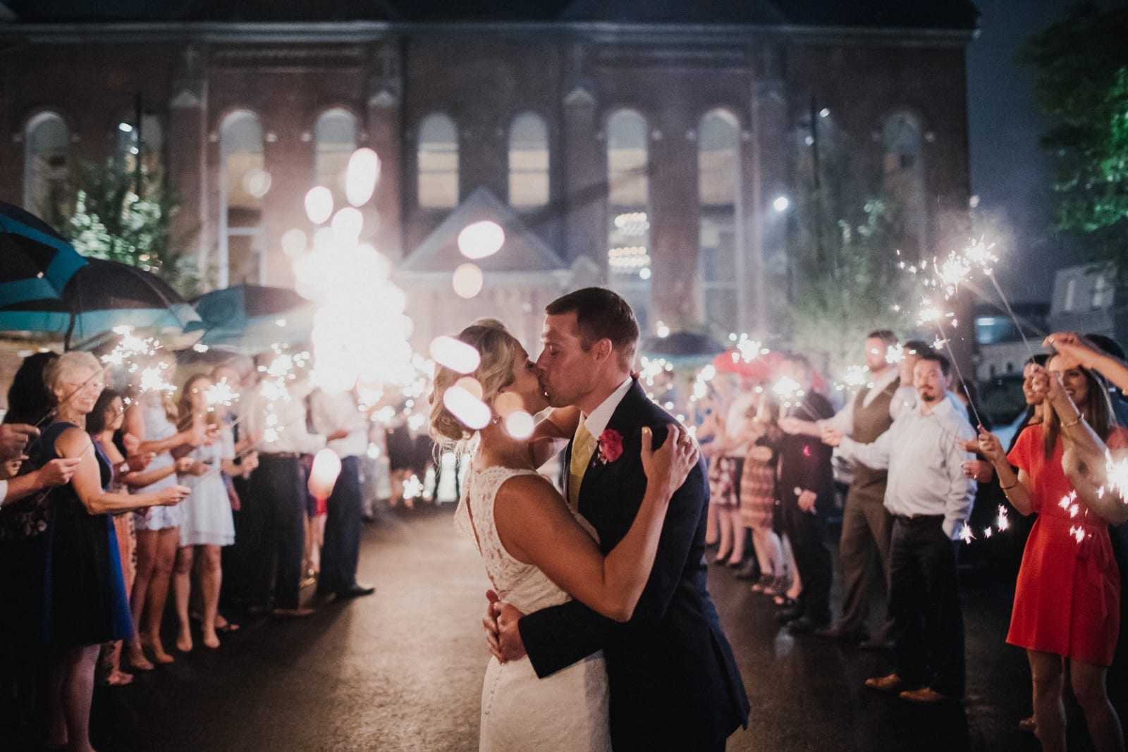 couple kisses while crowd holds sparklers at The Monastery Wedding - Cincinnati Wedding Photographer