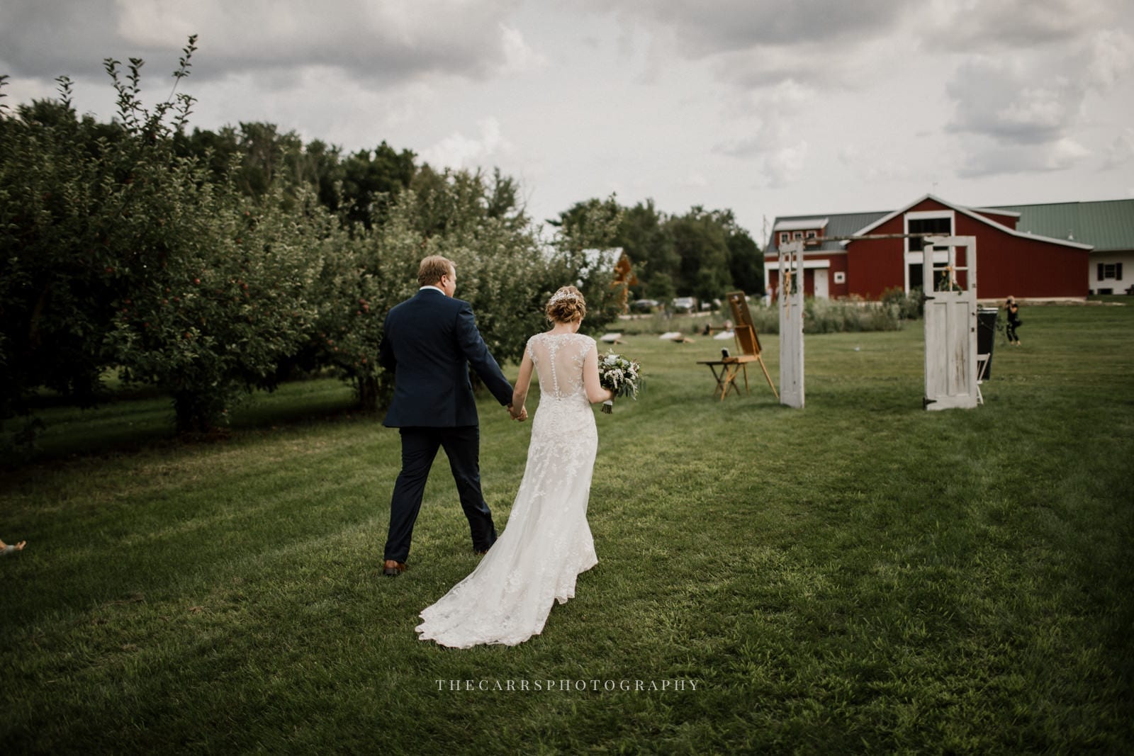 bride and groom walk toward barn at Eckers Apple Farm Wedding - Destination Photographer