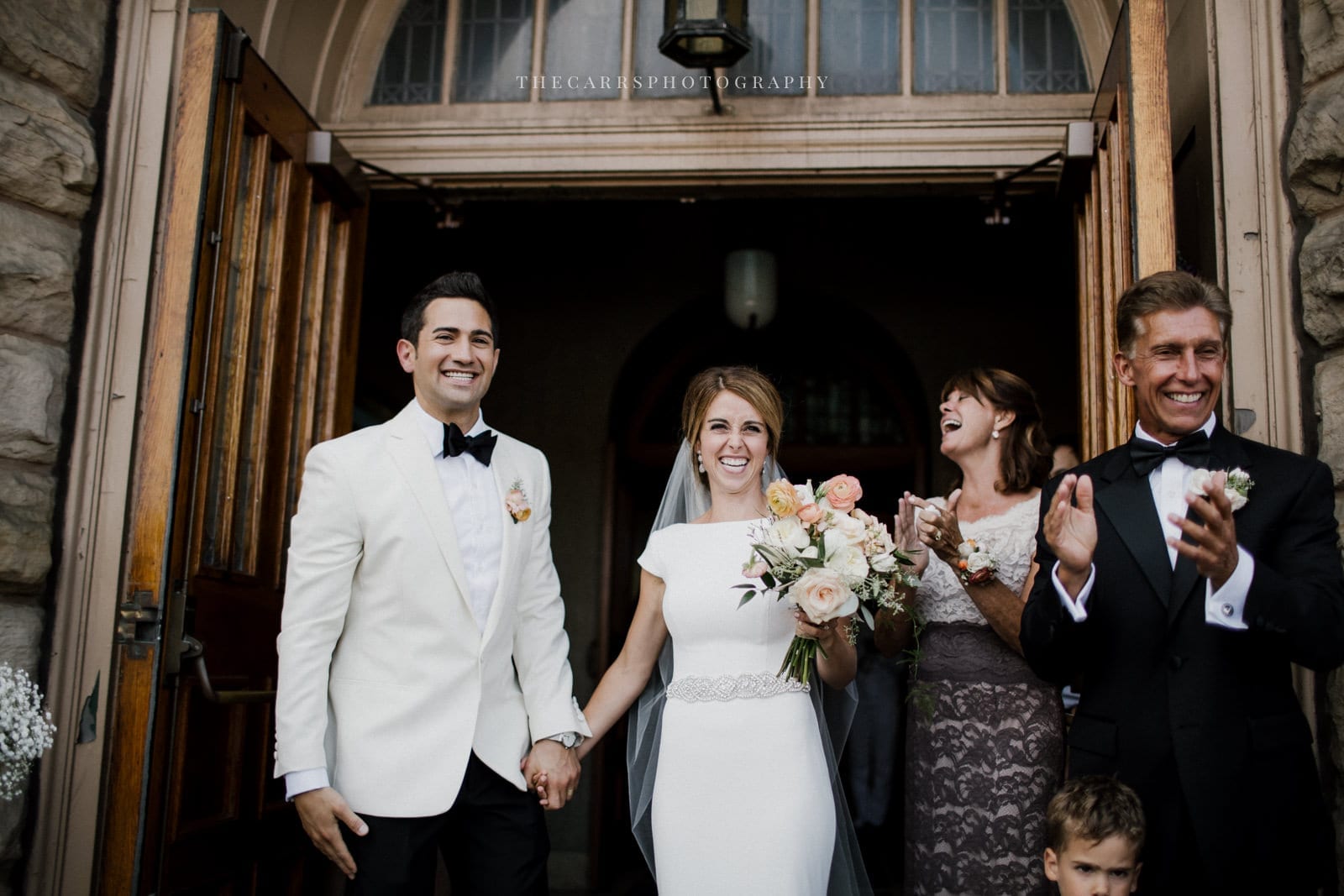 bride and groom smiling leaving church at lake house wedding - Akron Ohio Wedding Photographer