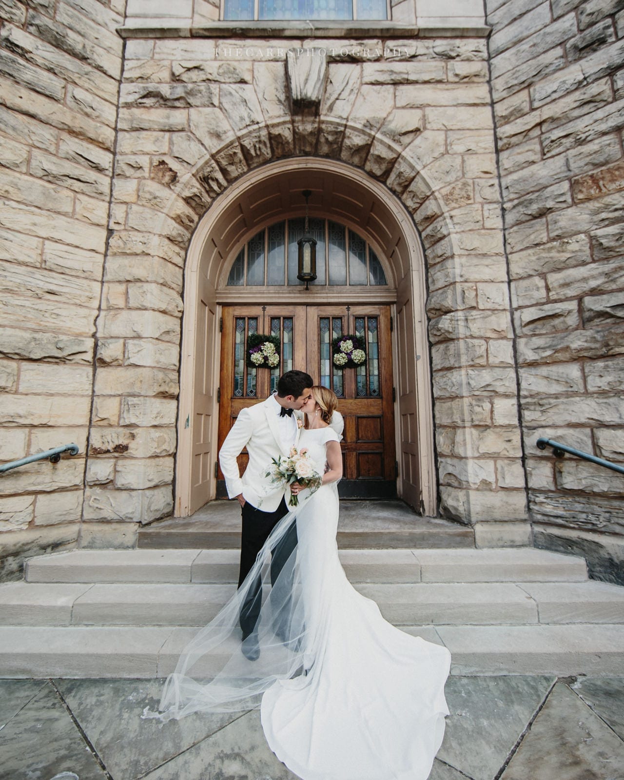 bride and groom kiss at church doors at lake house wedding - Akron Ohio Wedding Photographer