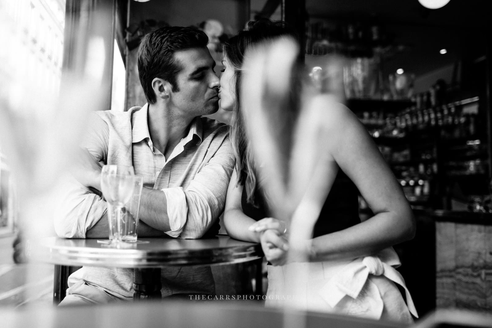 couple kisses in Parisian restaurant by Paris Engagement Photographer