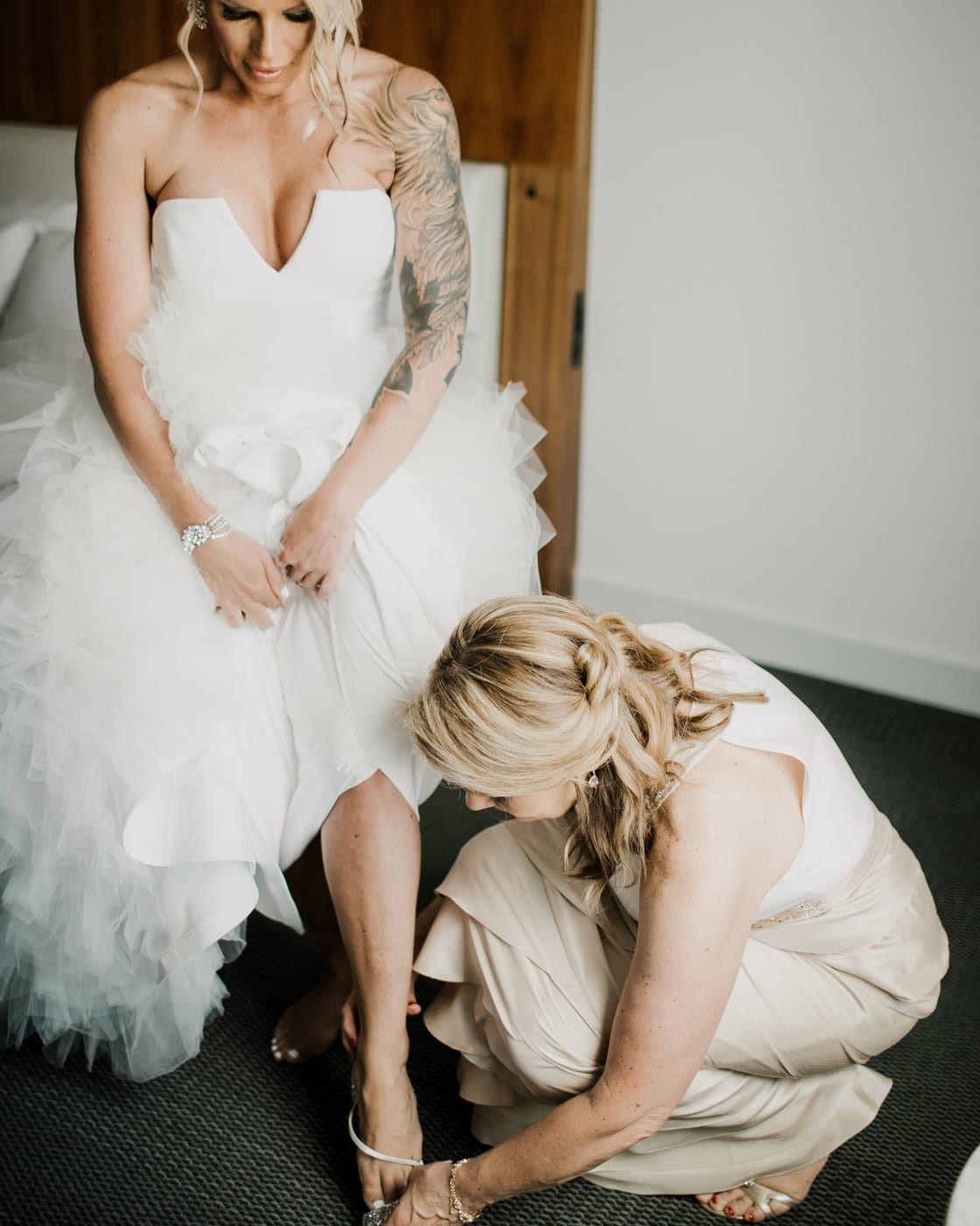 bride gets help putting on shoes at Juniper Rooftop Wedding