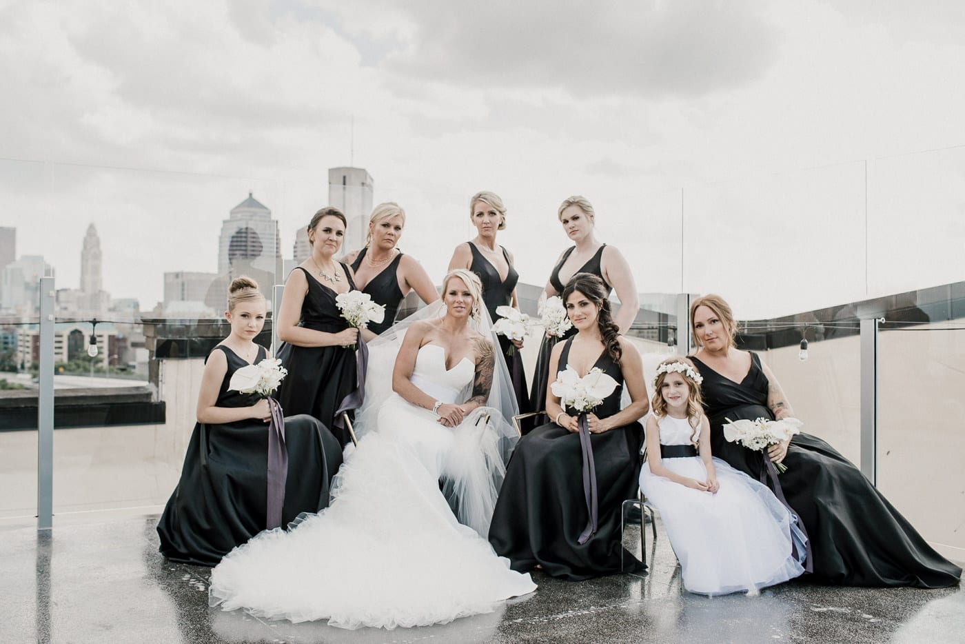 bride and bridesmaids sitting on roof at Juniper Rooftop Wedding