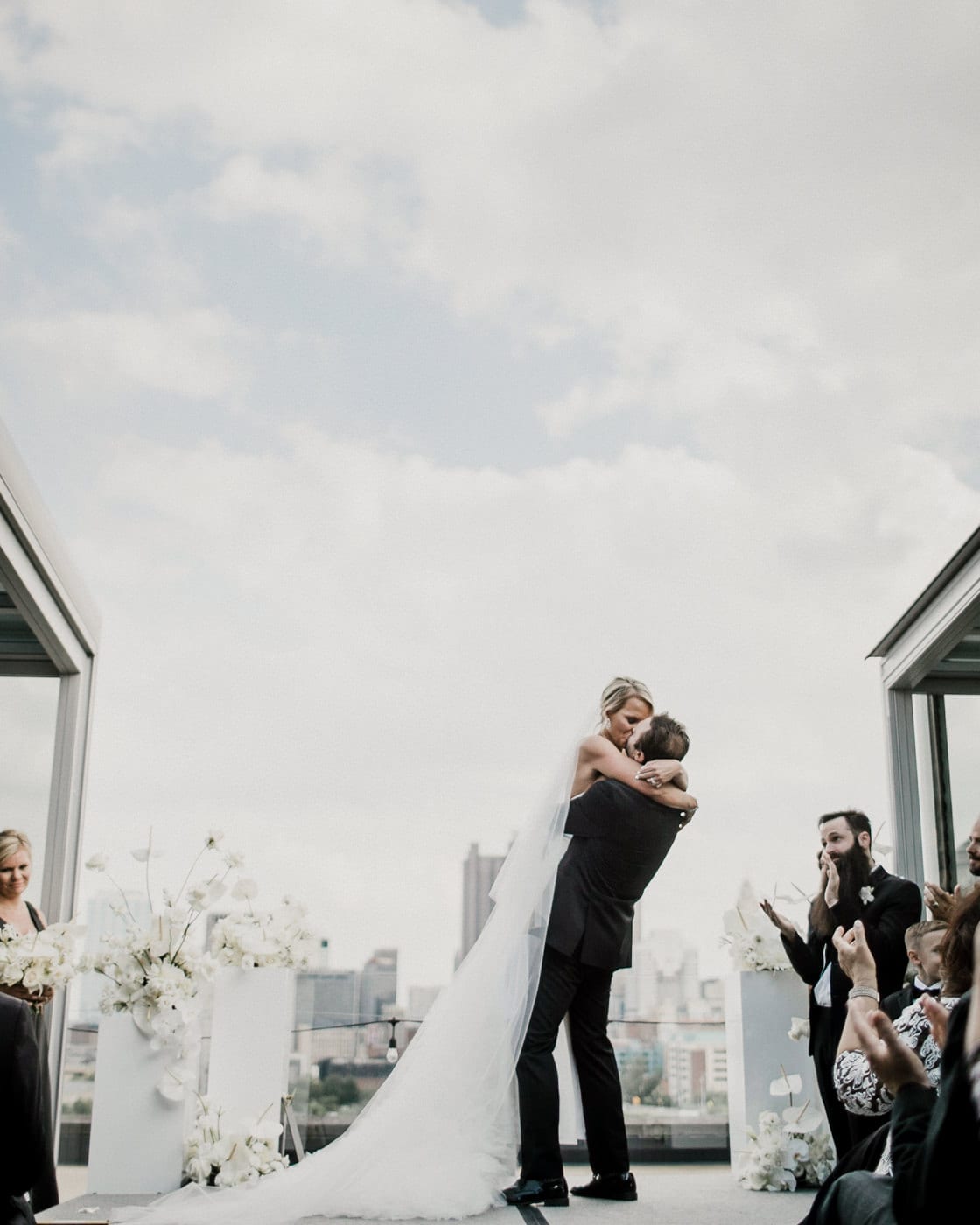 bride and groom kiss with city in background at Juniper Rooftop Wedding