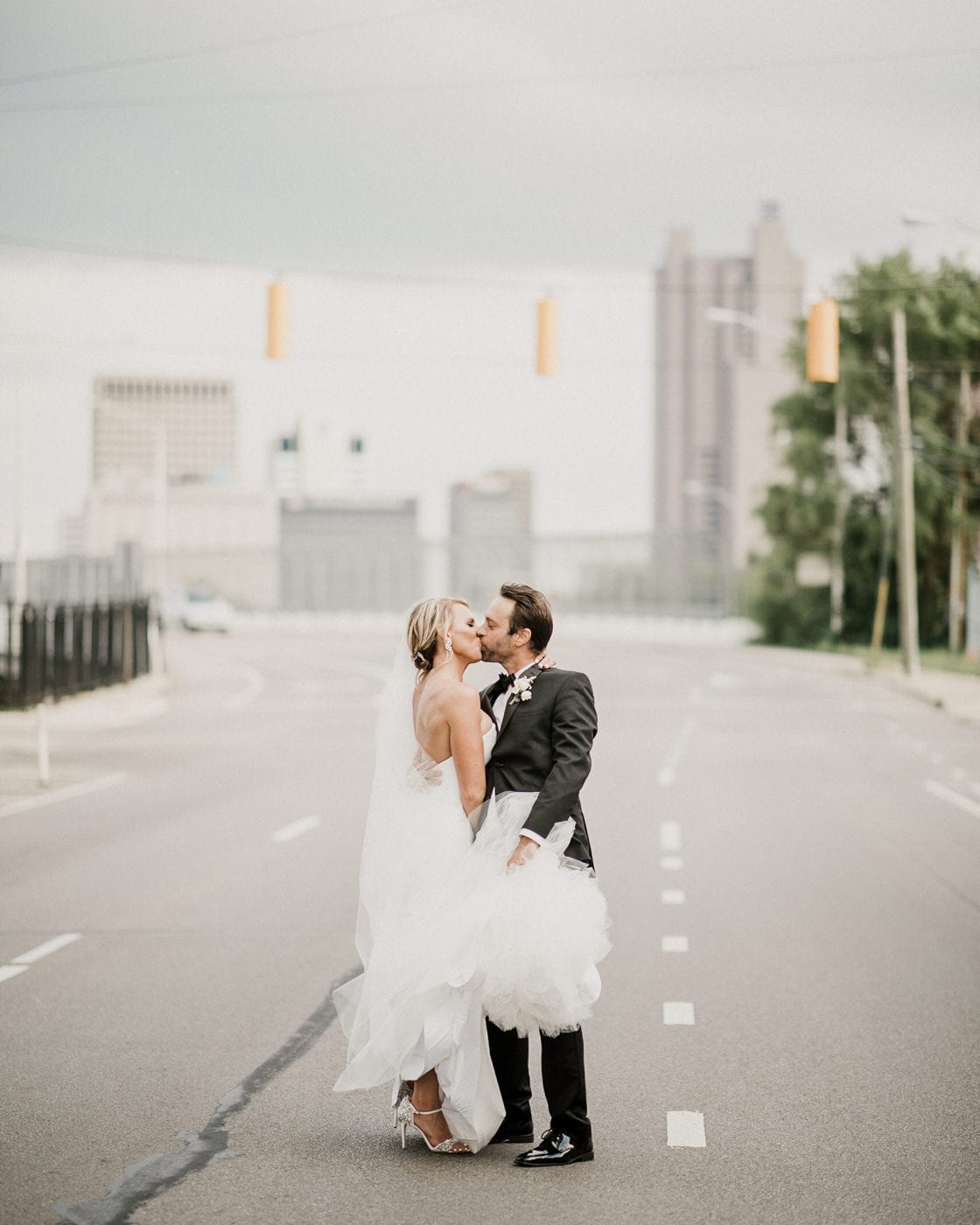 bride and groom kiss in the middle of the street at Juniper Rooftop Wedding