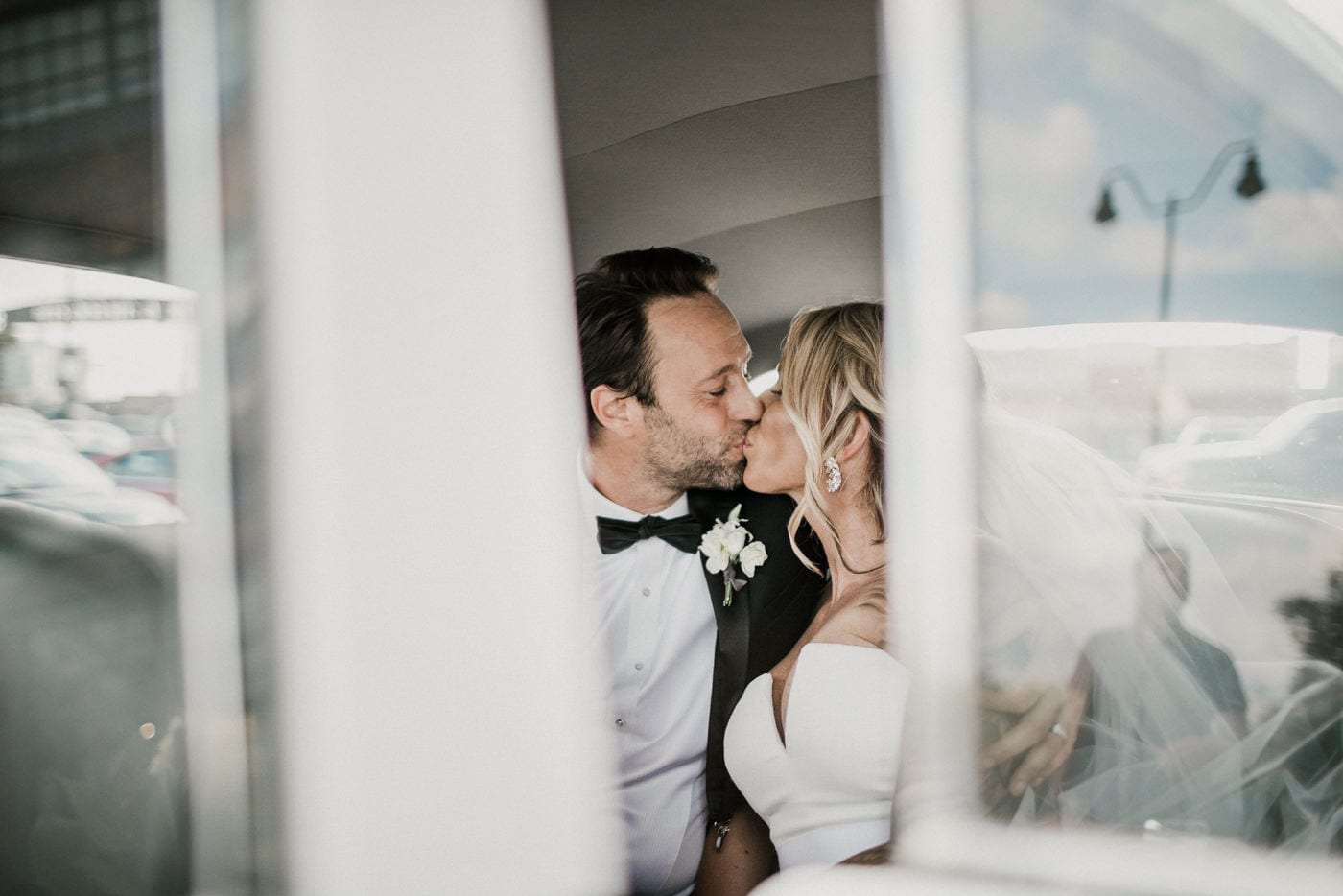 bride and groom kiss in vintage car at Juniper Rooftop Wedding