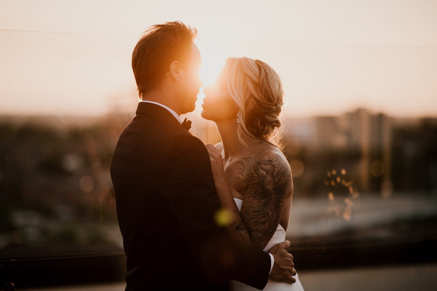 bride and groom kiss at sunset at Juniper Rooftop Wedding