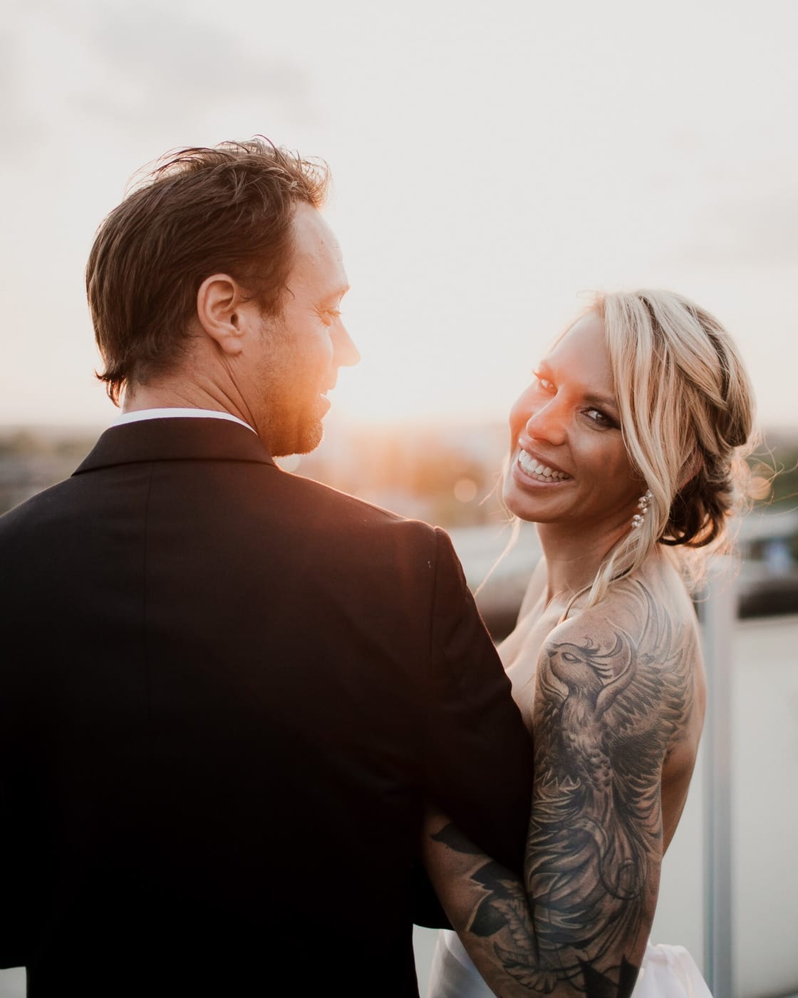 bride laughs and smiles while groom looks at her at Juniper Rooftop Wedding