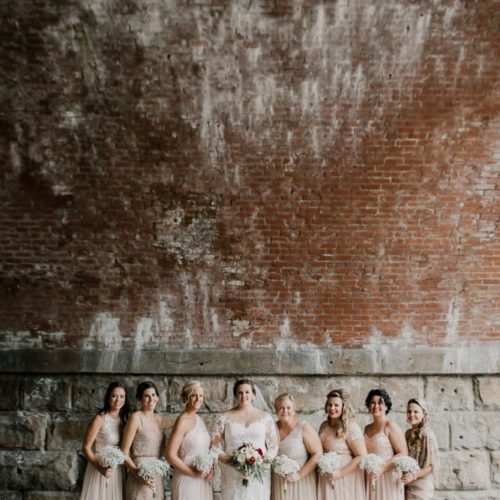 bride and bridesmaids with flowers in front of brick wall by Dayton Ohio Photographer Kera Estep