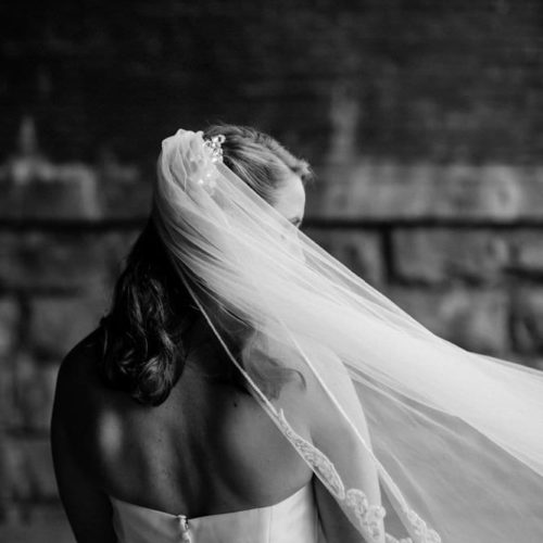 Bride covered in veil looks at photographer by Dayton Ohio Photographer Kera Estep