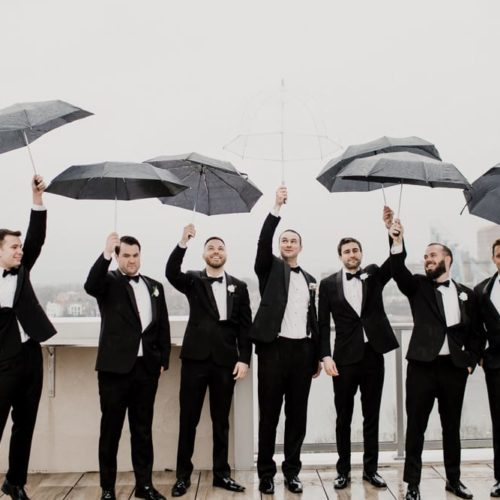 Groom and Groomsmen hold umbrellas in the rain by Dayton Ohio Photographer Kera Estep