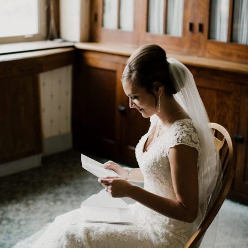 bride reads letter sitting in chair by Dayton Ohio Photographer Kera Estep
