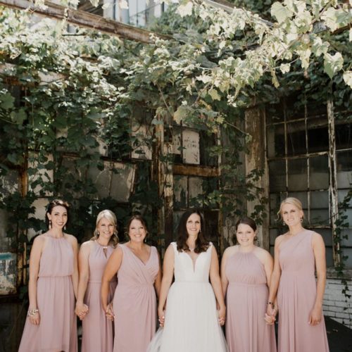 bride and bridesmaids hold hands under ivy by Dayton Ohio Photographer Kera Estep
