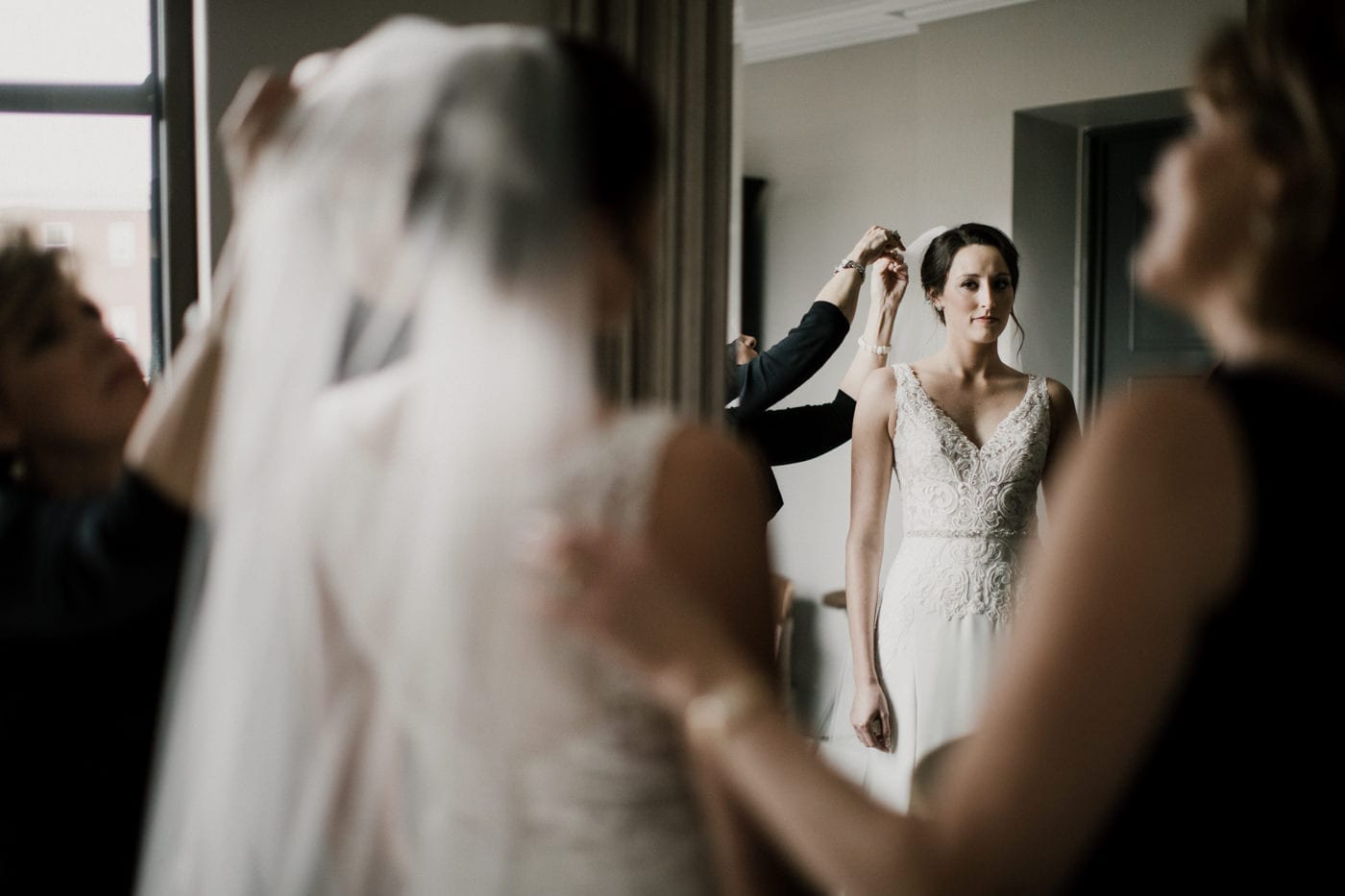 bride gets help fixing veil at black tie winter wedding