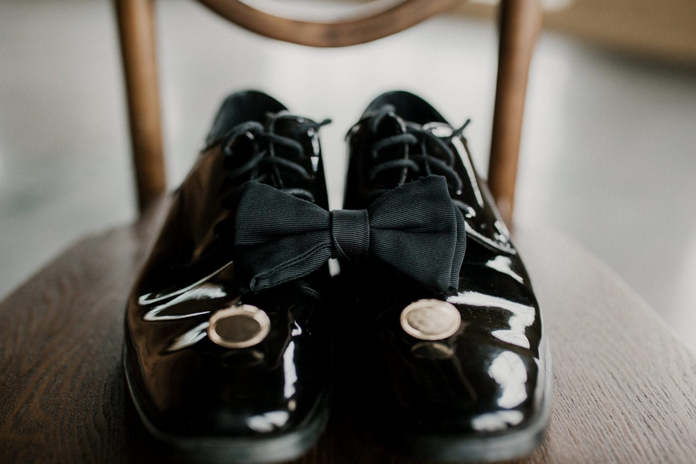close up of groom's shoes and bowtie on chair at black tie winter wedding