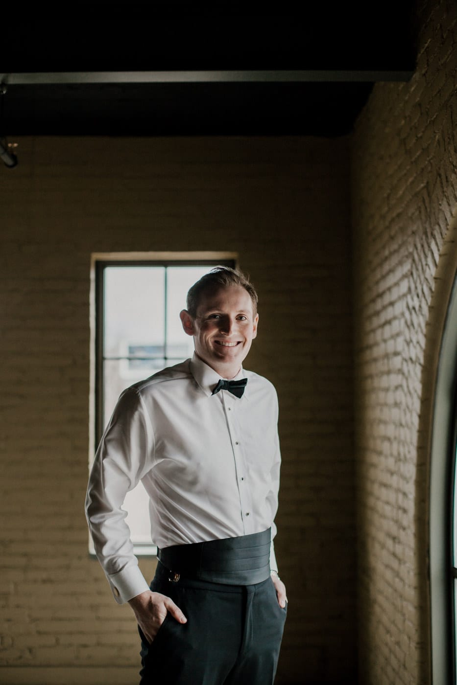 groom smiling with jacket off at black tie winter wedding