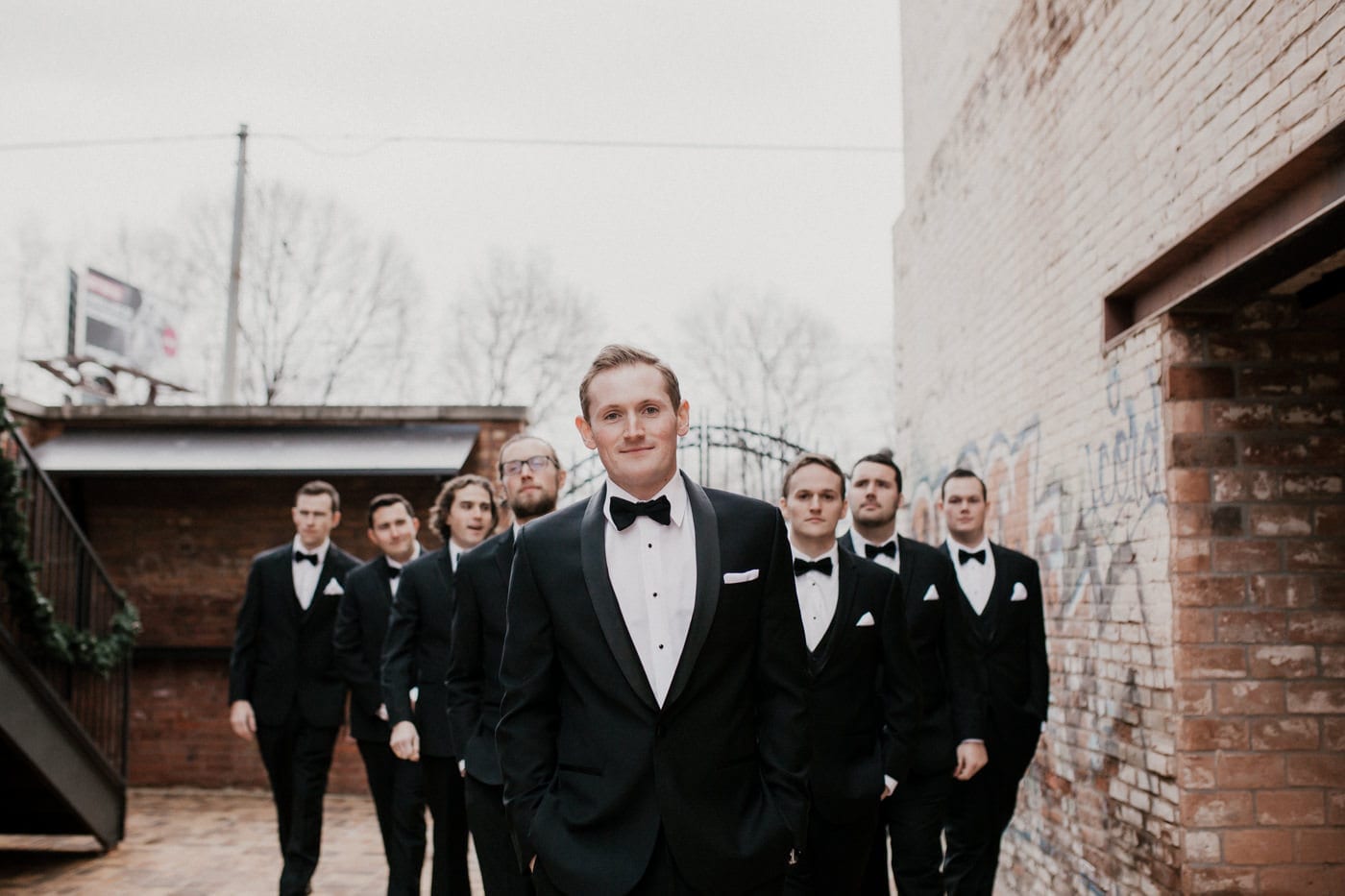 groom with groomsmen standing behind him at black tie winter wedding
