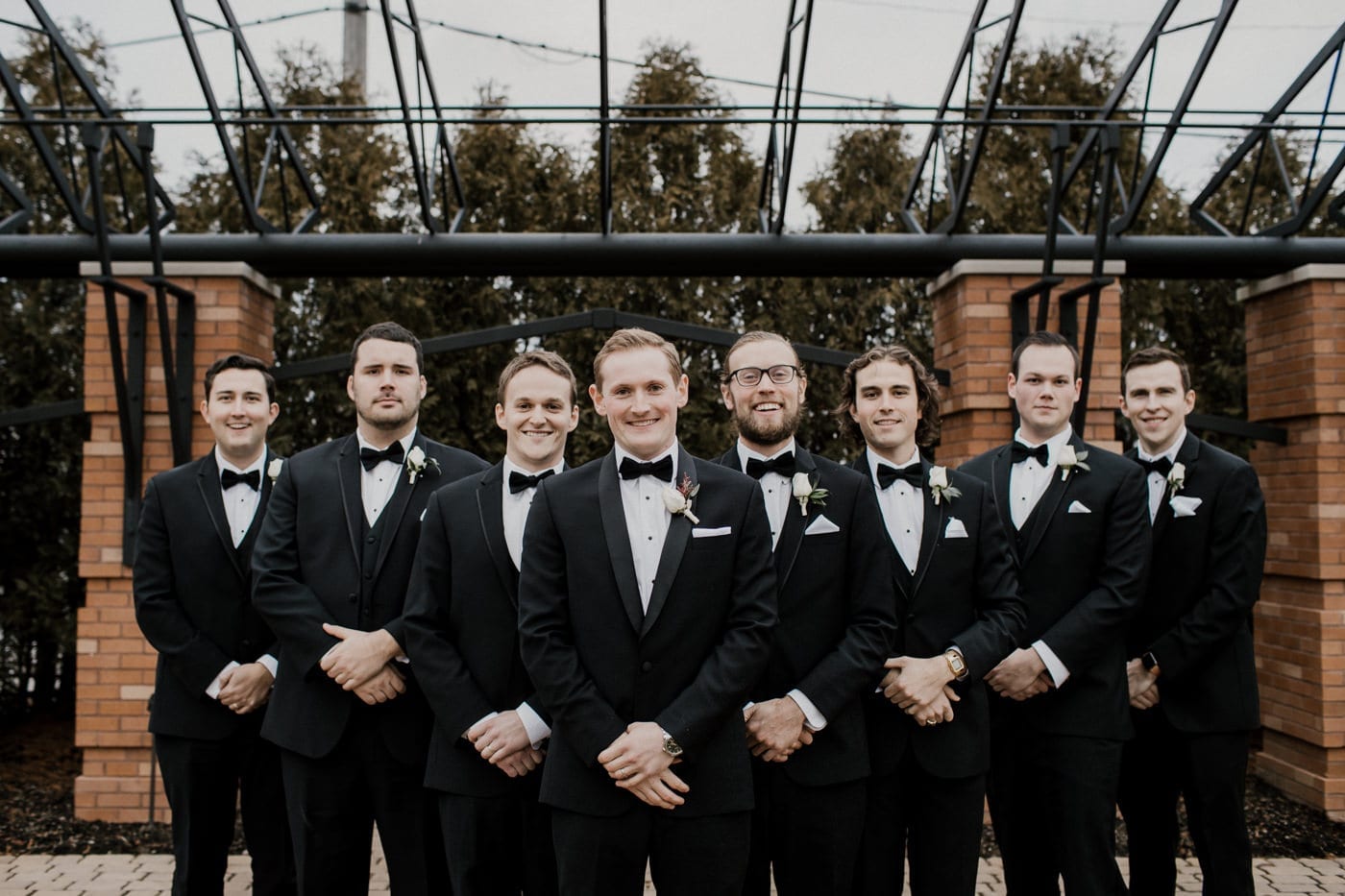 groom and groomsmen smile at black tie winter wedding
