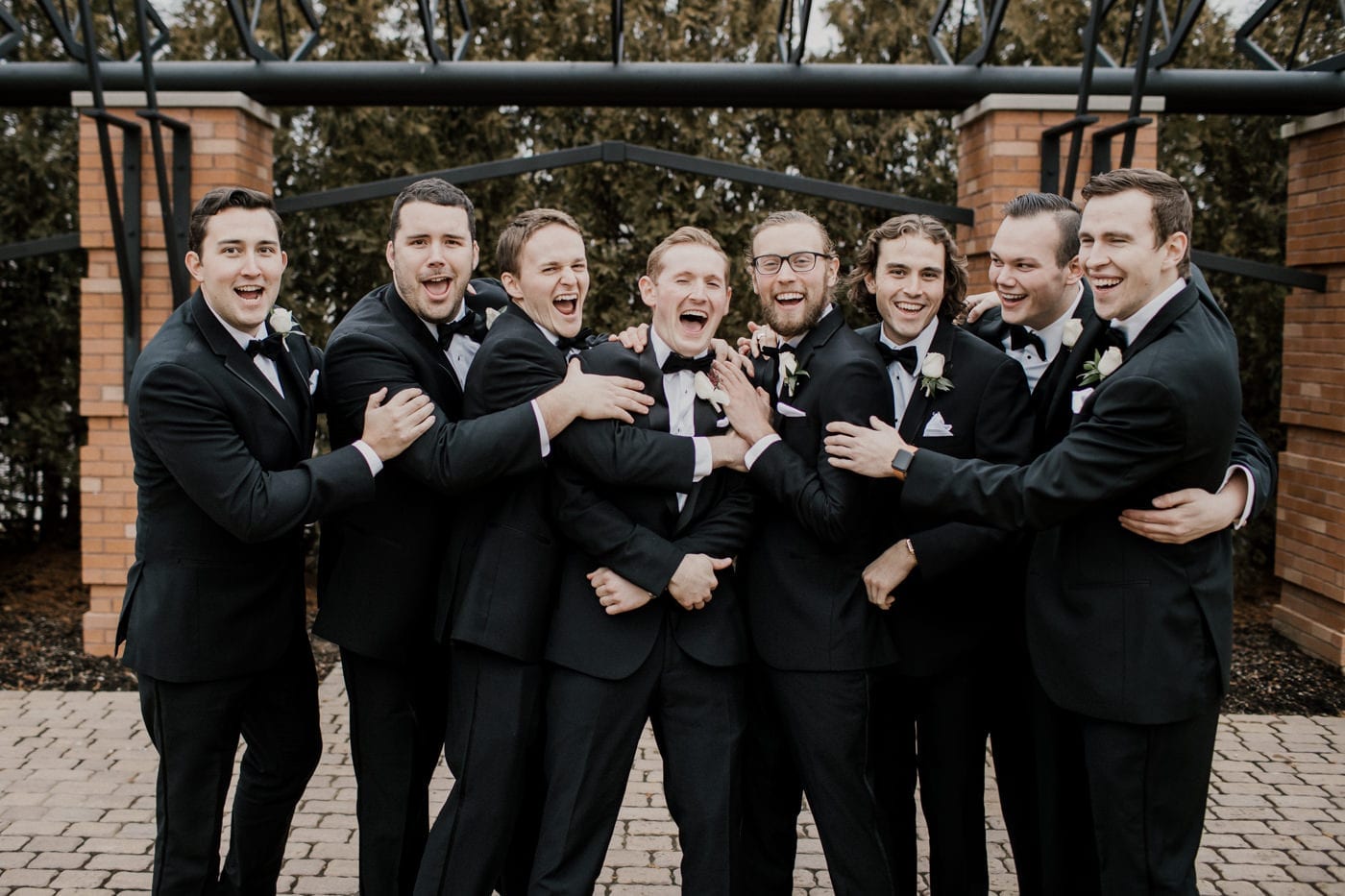 goofy picture of groom and groomsmen laughing at black tie winter wedding