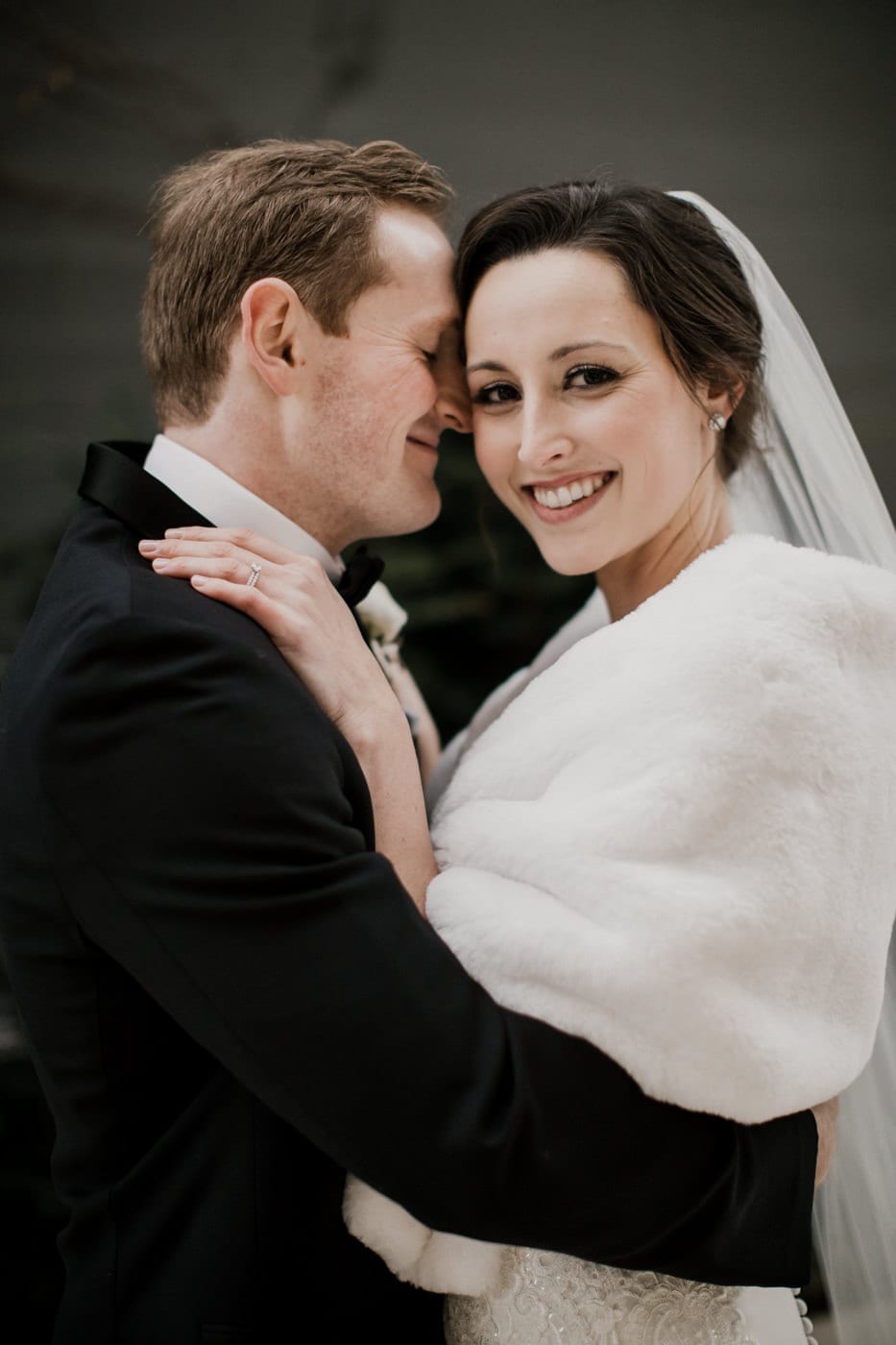 bride smiles while embracing groom at black tie winter wedding