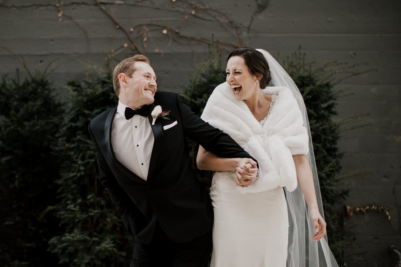 bride and groom holding hands and laughing at black tie winter wedding