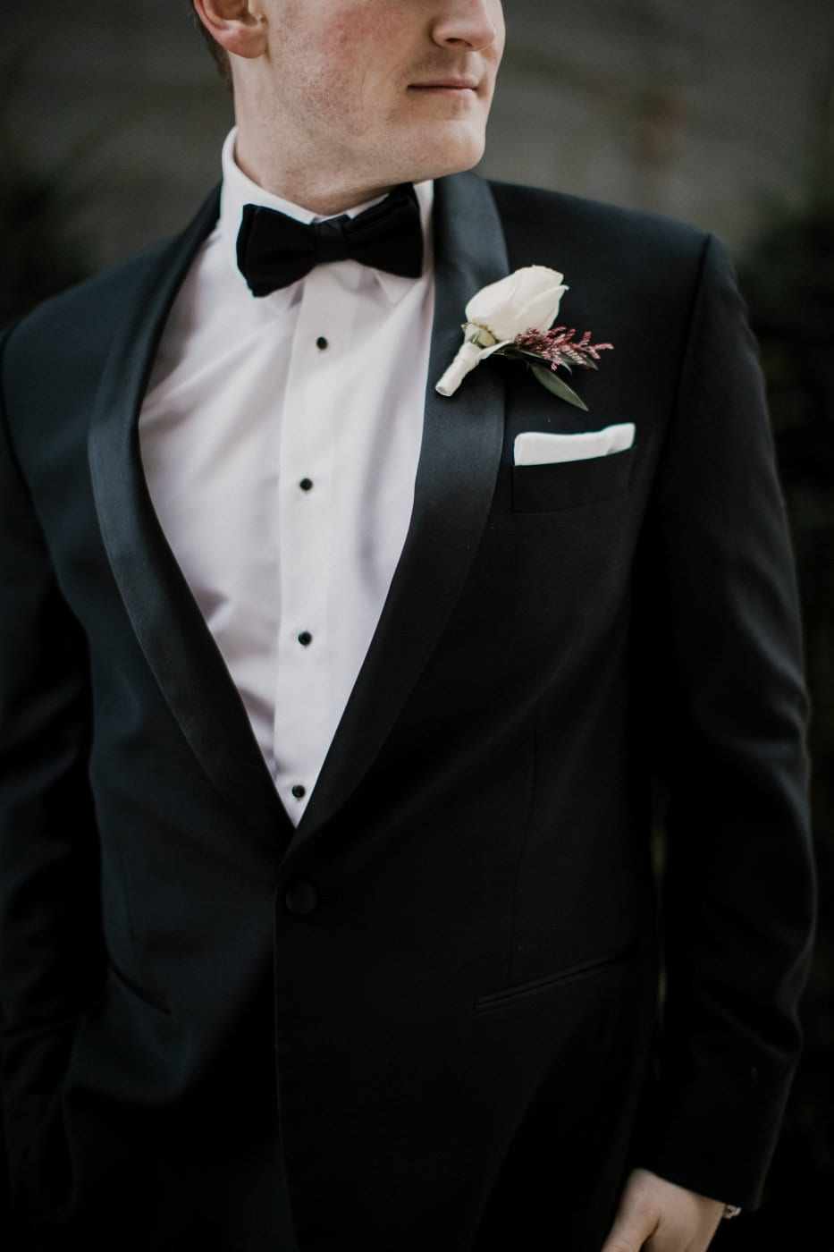 close up of grooms white rose boutonniere at black tie winter wedding