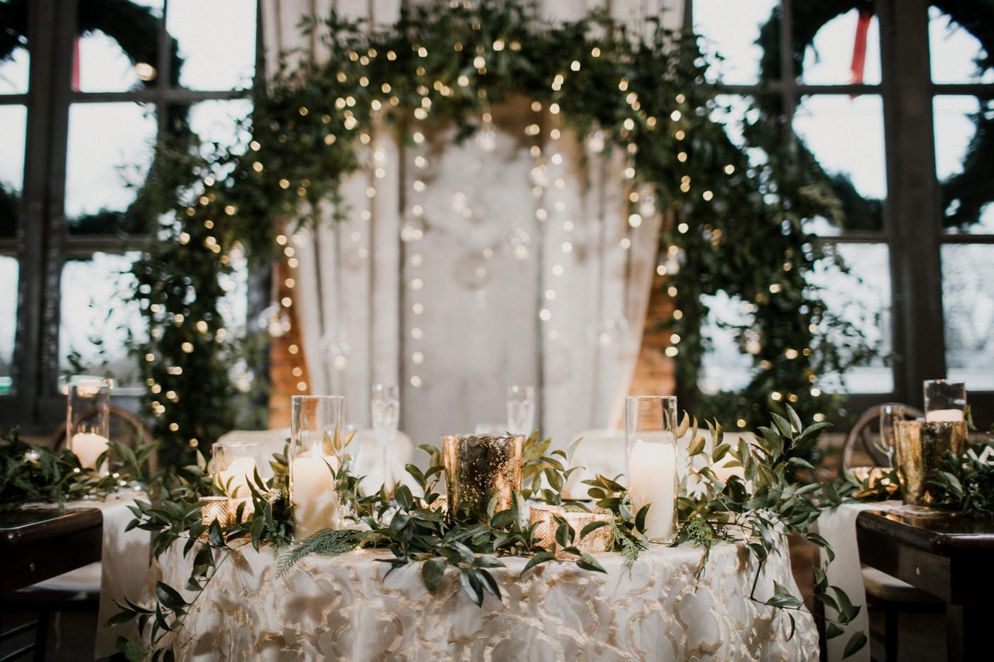 sweetheart table with large lighted wreath at black tie winter wedding