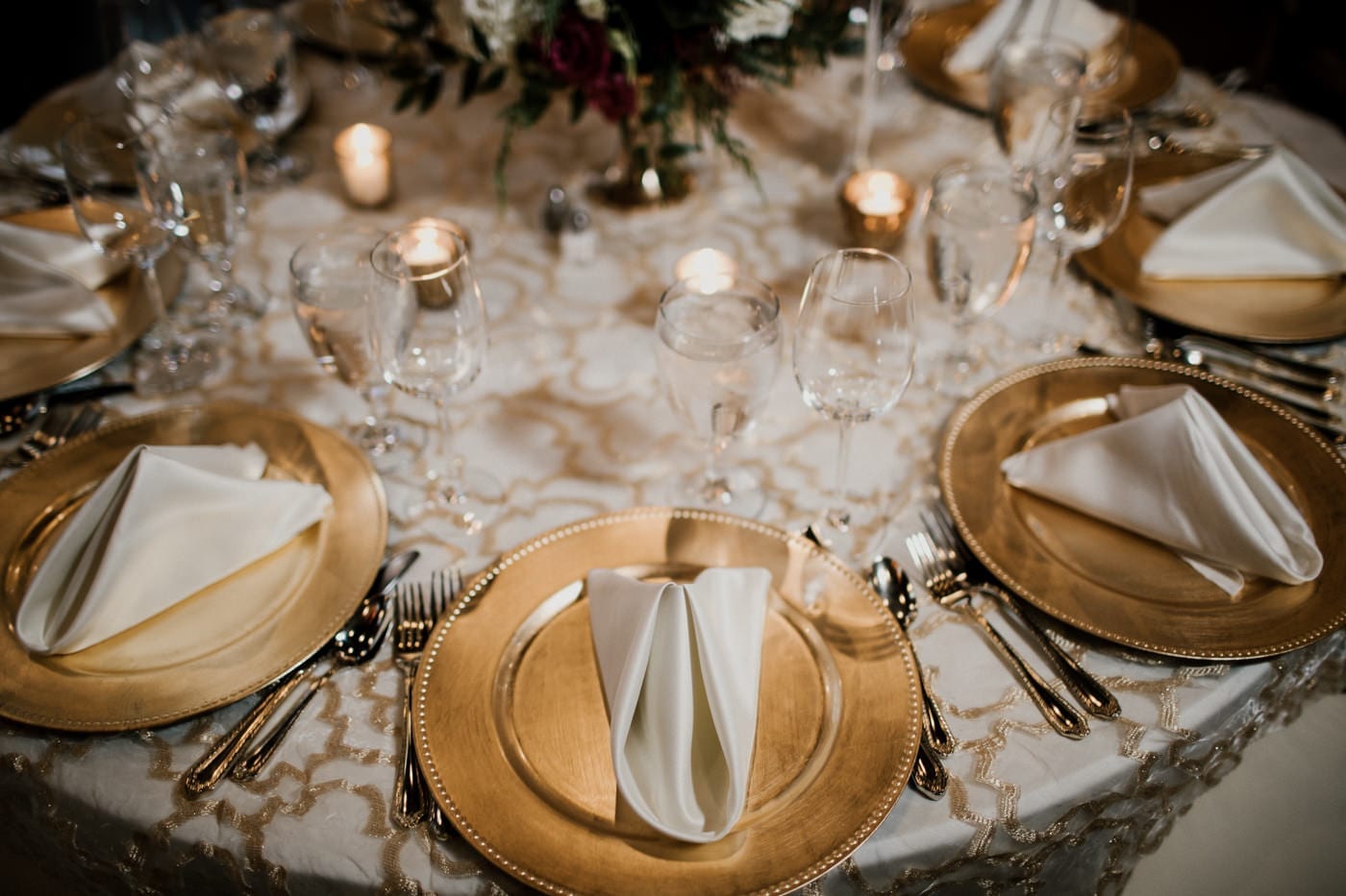 reception table with gold chargers and folded napkins at black tie winter wedding