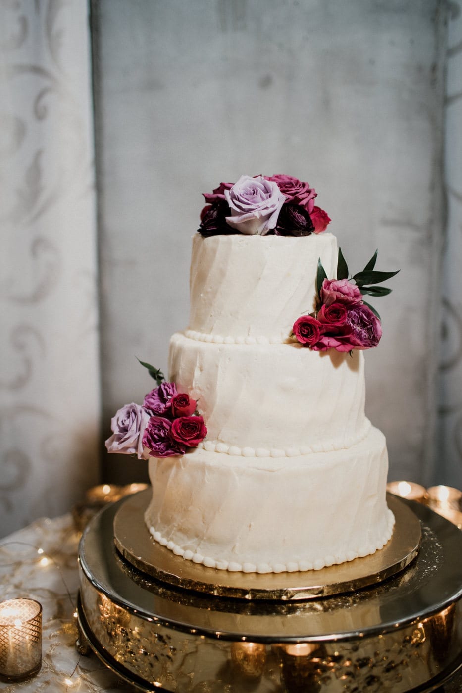 wedding cake with purple and red roses at black tie winter wedding