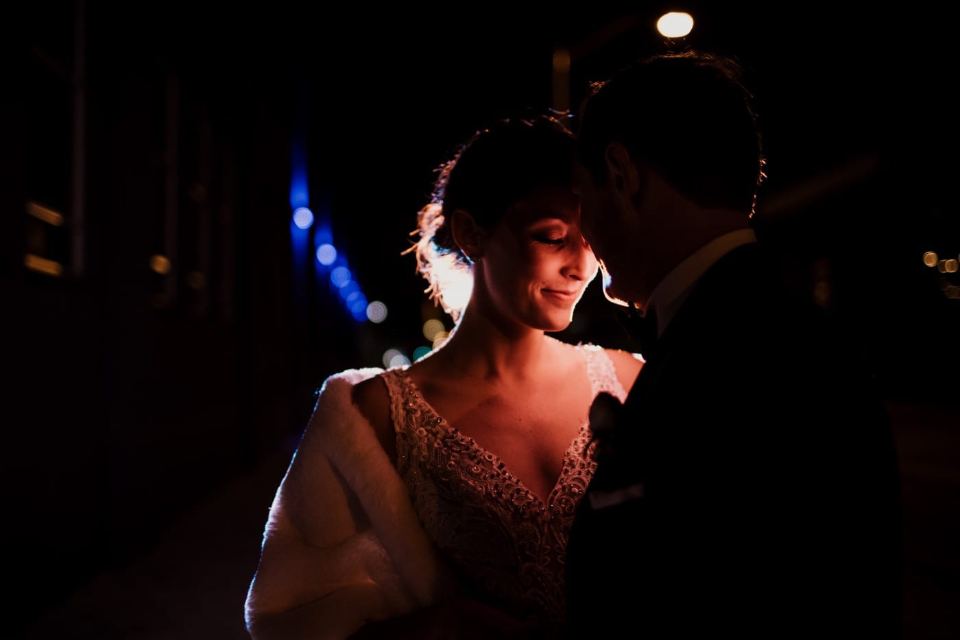 bride and groom foreheads together low lighting at black tie winter wedding