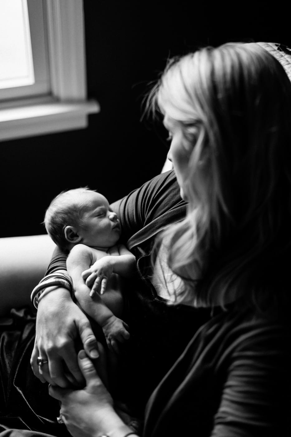 mom holding new born looking down at him - in-home newborn session