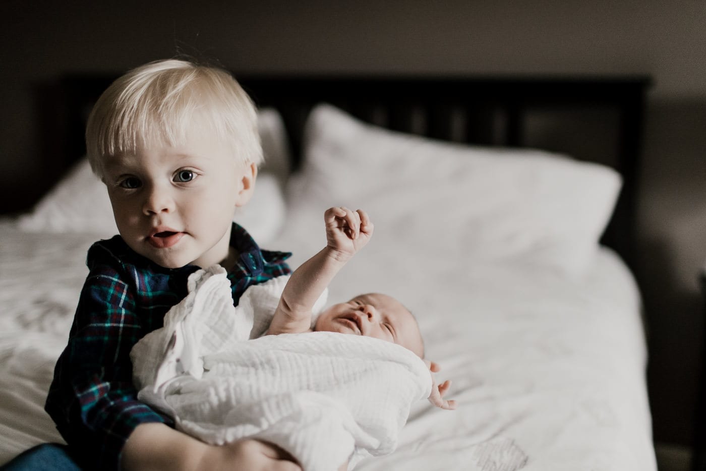 big brother holds baby brother on bed - in-home newborn session