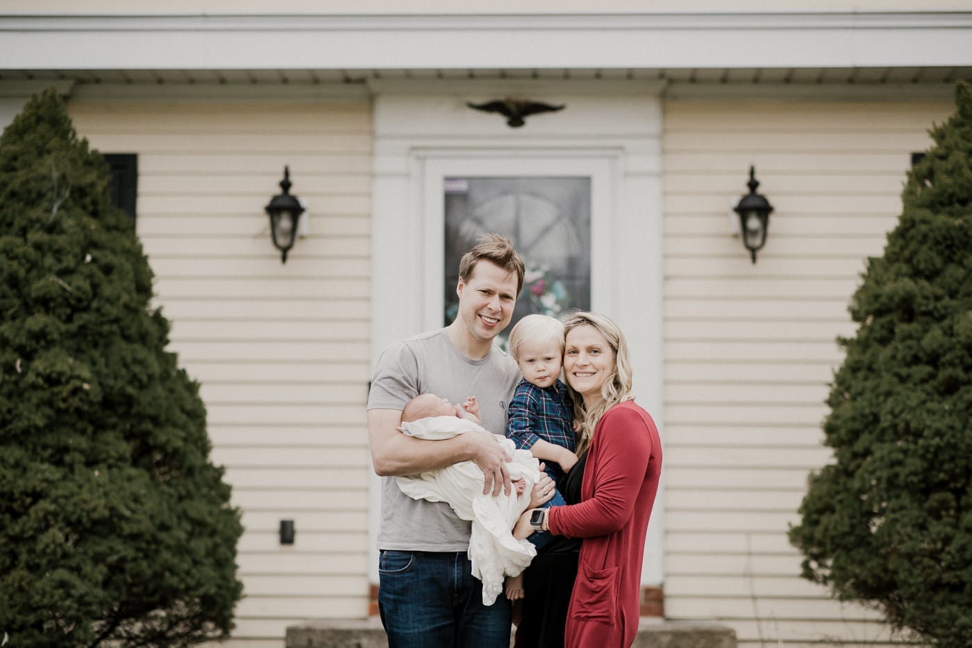 mom dad big brother and new baby in front of house - in-home newborn session