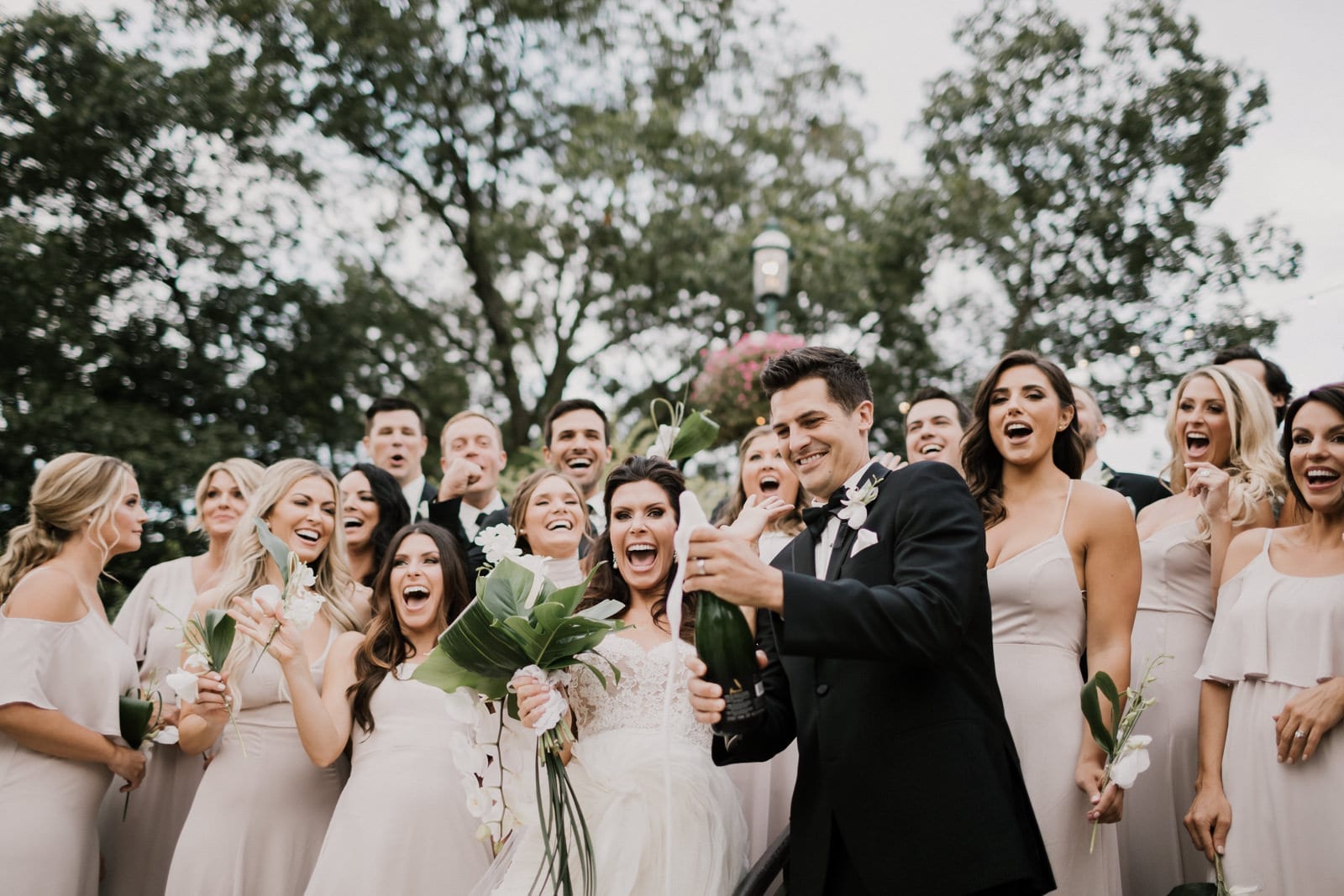 groom popping champagne bottle with bridal party at Franklin Park Conservatory Wedding by Columbus Wedding Photographer