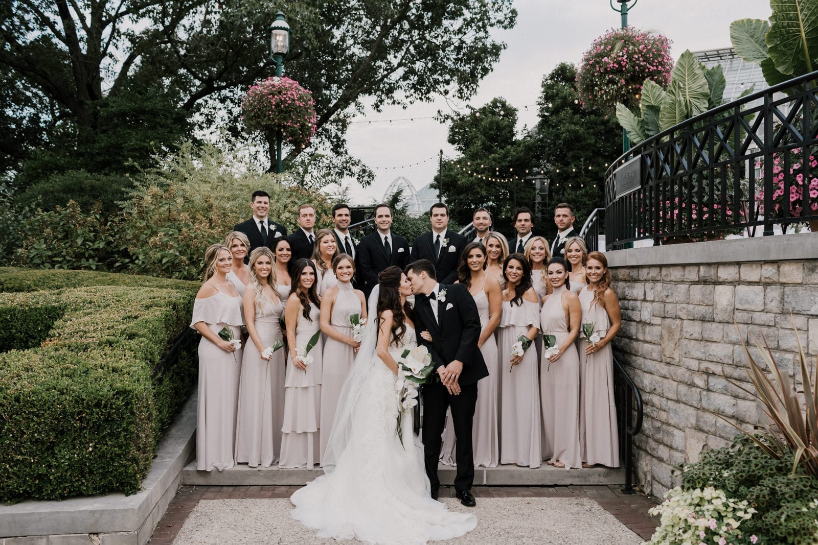 bride and groom kiss in front bridal party of at Franklin Park Conservatory Wedding by Columbus Wedding Photographer
