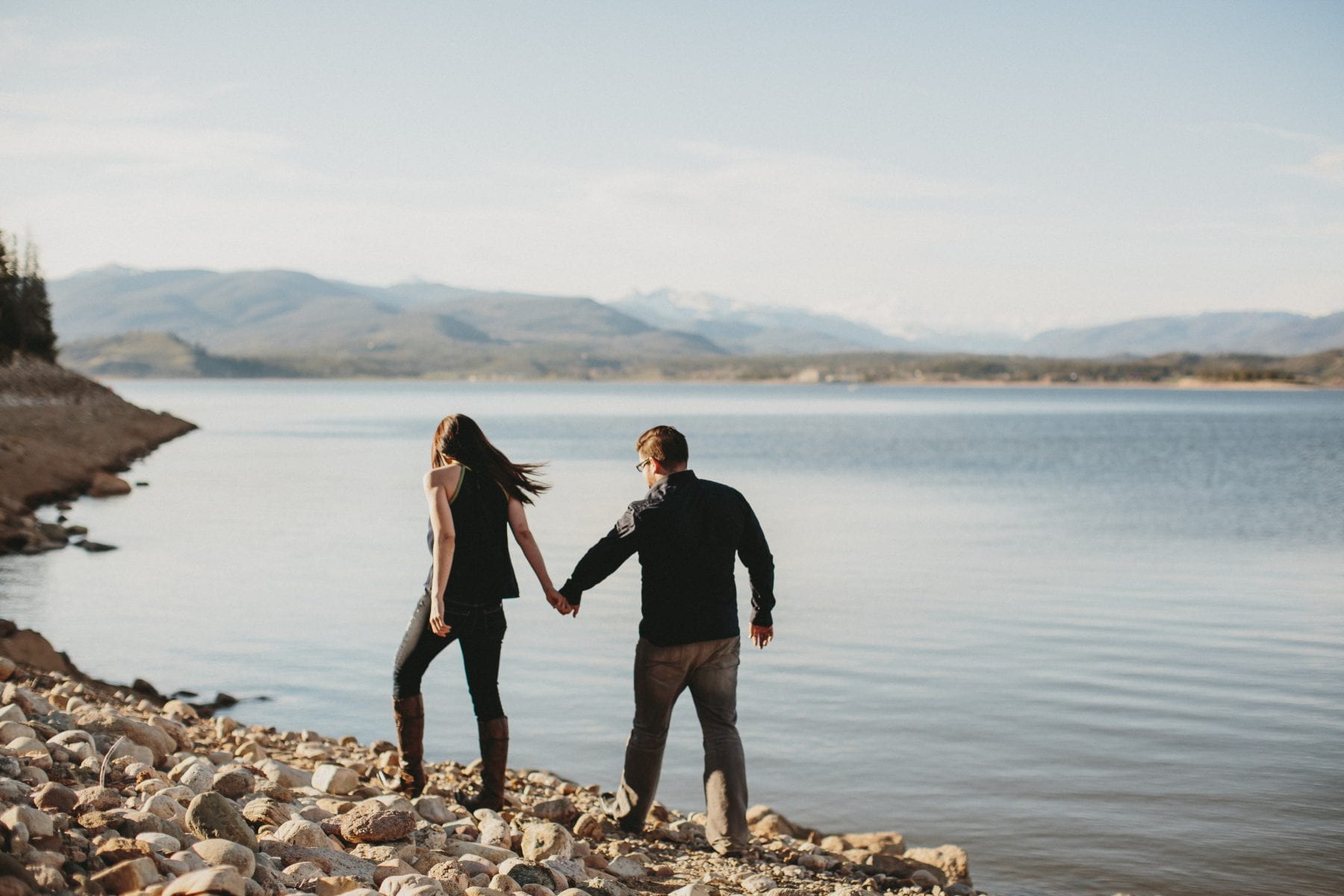 couple holds hands and walks along lake shore Grand Lake Colorado Family Portraits - Destination Photographer