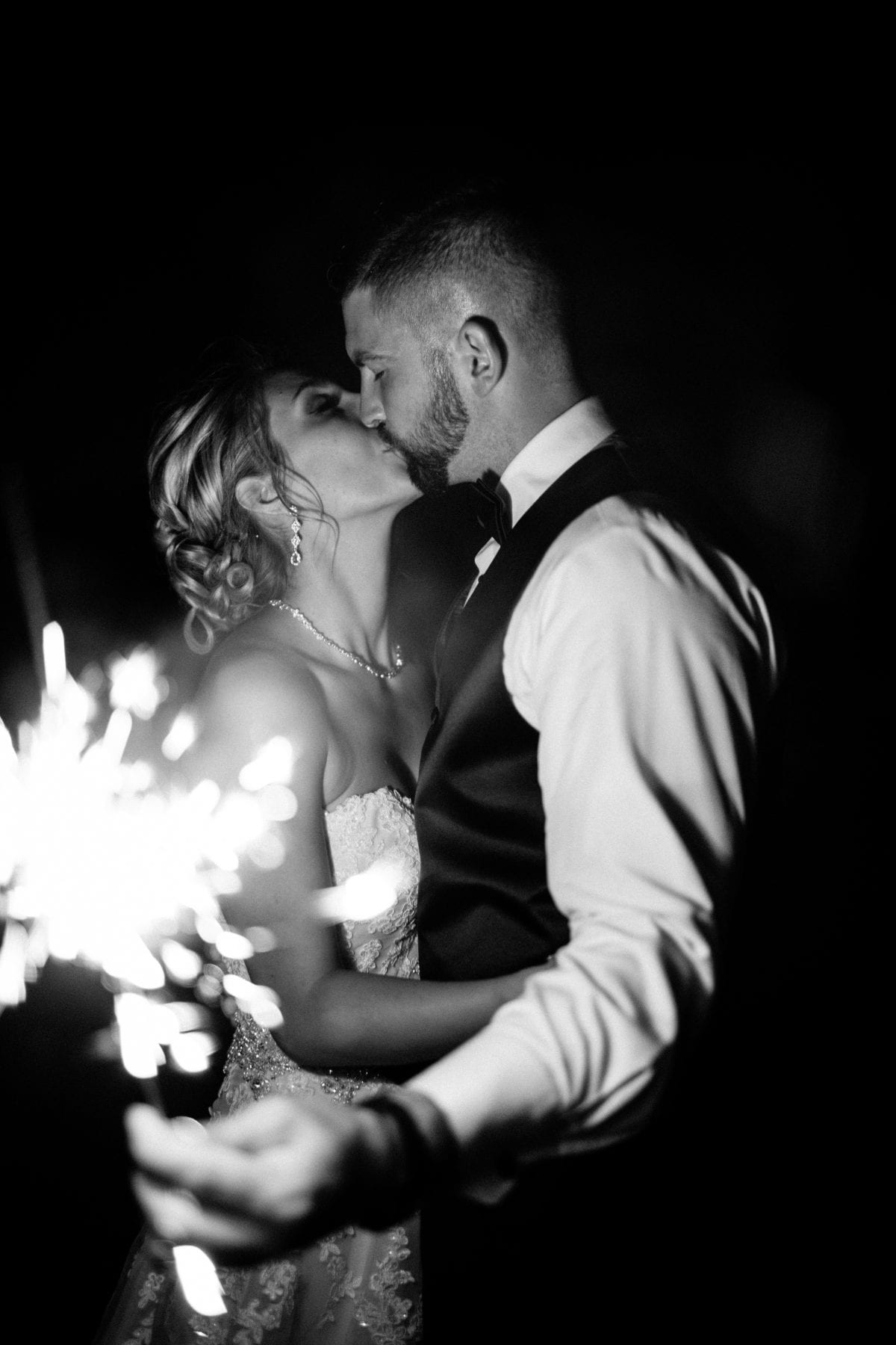 bride and groom kiss while holding sparkler at Rolling Meadows Ranch Wedding - Cincinnati Wedding Photographer