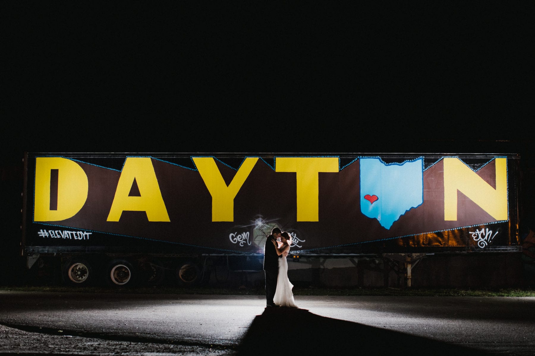 bride and groom kiss in front of Dayton sign at Top of the Market Wedding - Dayton Wedding Photographer