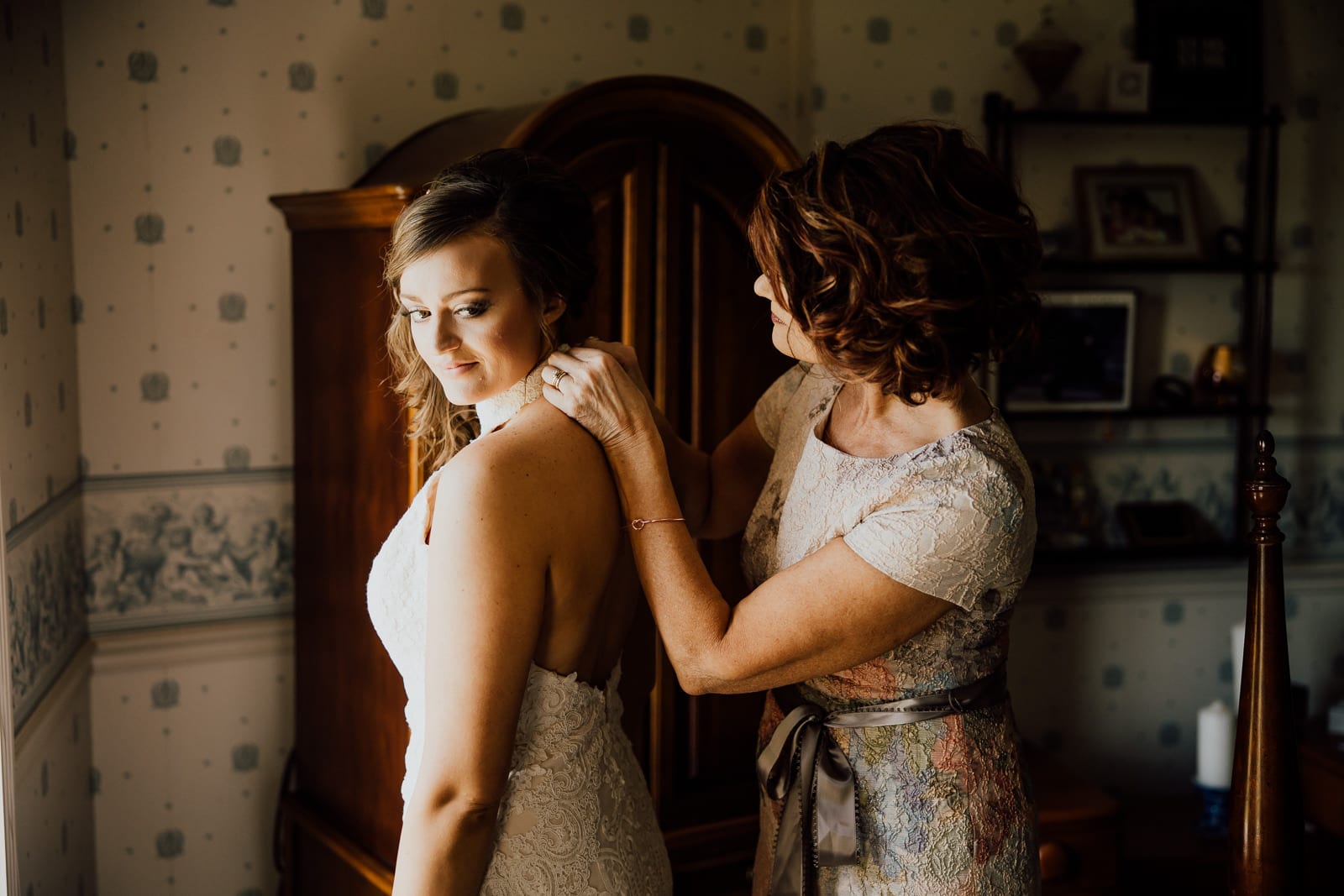 Mother helps bride fasten wedding dress