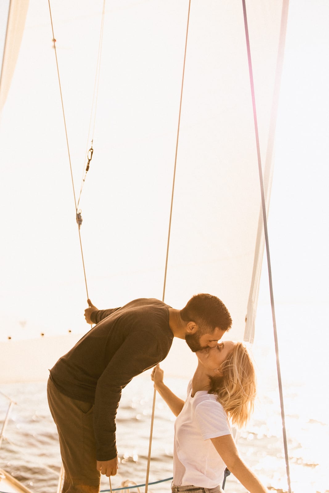 Couple kisses in sunlight on boat