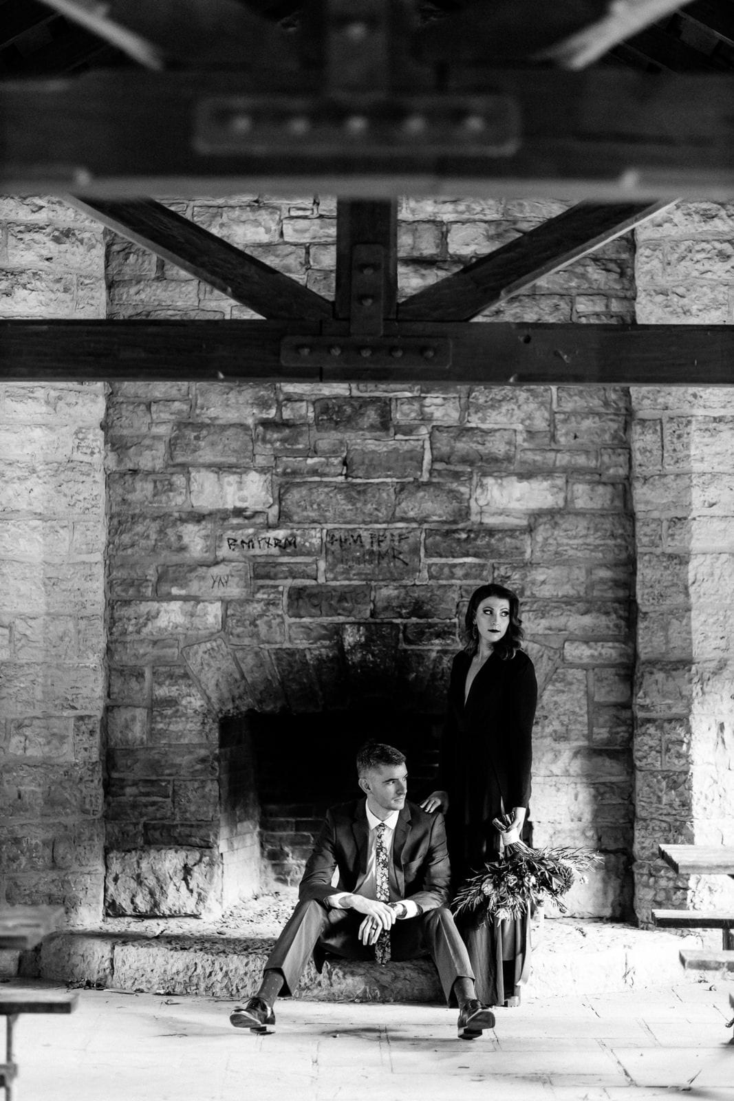 Bride and groom pose elegantly by fireplace