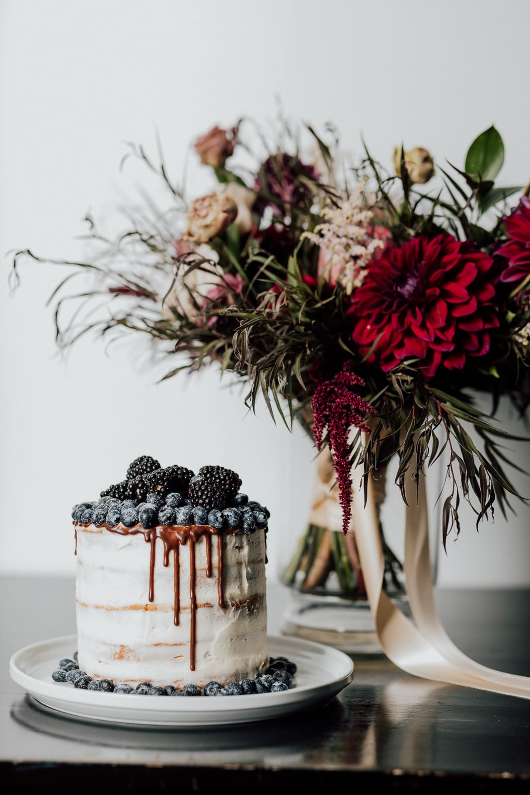 Wedding cake with berries and wedding flowers in vase