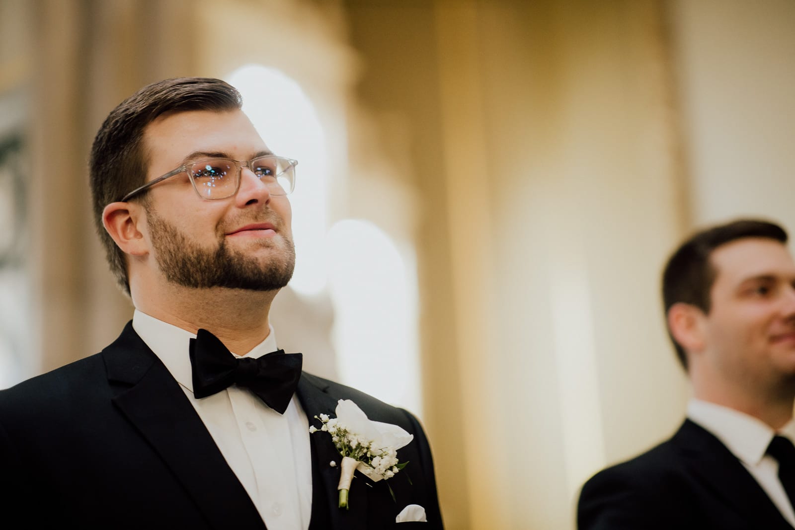 groom smiles watching bride come down the aisle