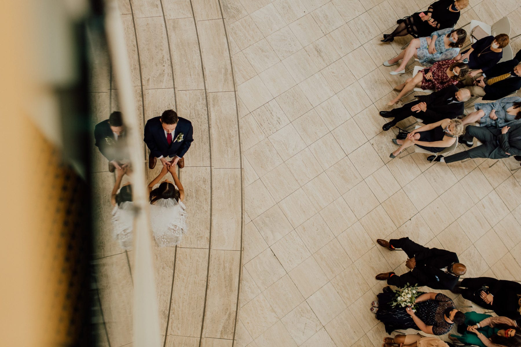 Bride and groom hold hands at the alter from above