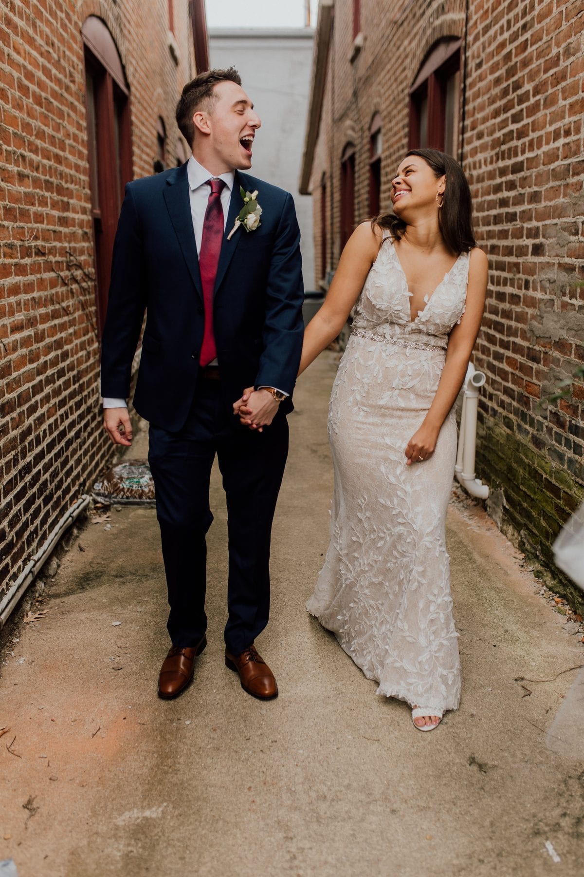 Bride and groom laugh in alleyway