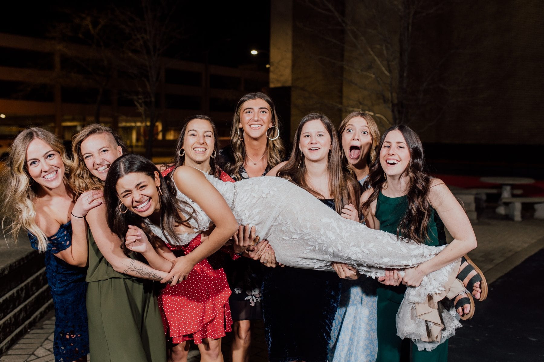 Bridesmaids hold bride up while she laughs